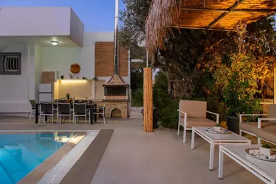 an outdoor patio with a pool and a table and chairs at Amazing Summer Villa in Kolimbia