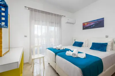 a bedroom with two beds with blue and white sheets at Amazing Summer Villa in Kolimbia