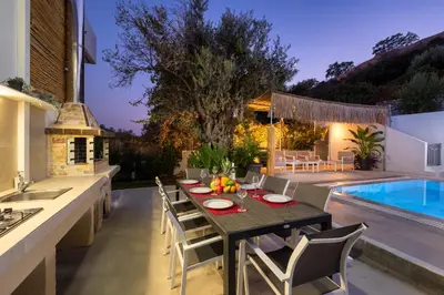 a dining room with a table and chairs next to a pool at Amazing Summer Villa in Kolimbia