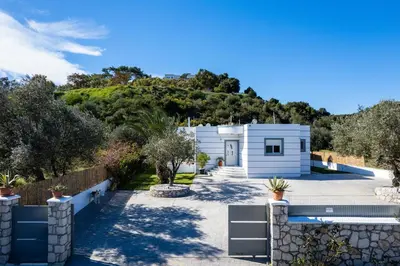 a white house with a hill in the background at Amazing Summer Villa in Kolimbia