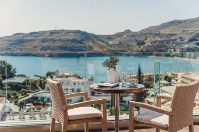a table and chairs on a balcony with a view of the water at Lindos Village Resort & Spa - Adults Only in Líndos