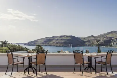 a table and chairs on a balcony with a view of the water at Lindos Village Resort & Spa - Adults Only in Líndos