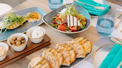 a table topped with plates of food and salads at Lindos Village Resort & Spa - Adults Only in Líndos
