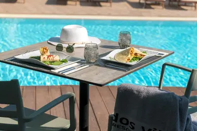 a table with two plates of food next to a pool at Lindos Village Resort & Spa - Adults Only in Líndos