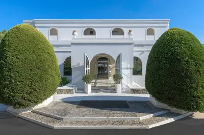 a white house with two large trees in front of it at Lindos Village Resort & Spa - Adults Only in Líndos