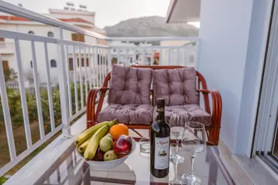 a bottle of wine and a bowl of fruit on a balcony at Casa Stergos 2apts in Archangelos