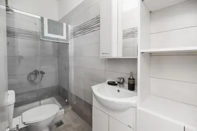 a white bathroom with a toilet and a sink at Casa Stergos 2apts in Archangelos