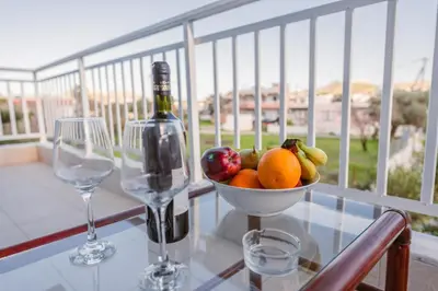 a glass table with a bowl of fruit and a bottle of wine at Casa Stergos 2apts in Archangelos