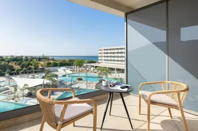 a balcony with a table and chairs and a view of the pool at Electra Palace Rhodes - Premium All Inclusive in Ialyssos