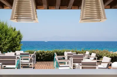a row of white chairs and the ocean at Electra Palace Rhodes - Premium All Inclusive in Ialyssos