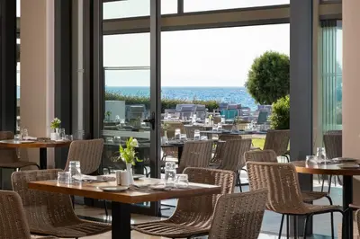 a restaurant with tables and chairs and a view of the city at Electra Palace Rhodes - Premium All Inclusive in Ialyssos