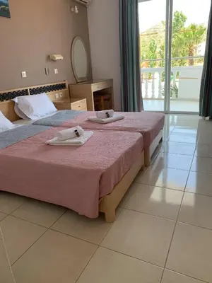 two beds in a hotel room with towels on them at White Palace Studios in Faliraki