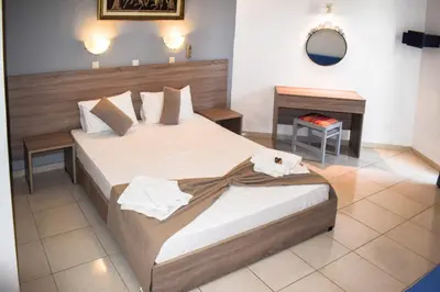 a bedroom with two beds and a table and a mirror at White Palace Studios in Faliraki