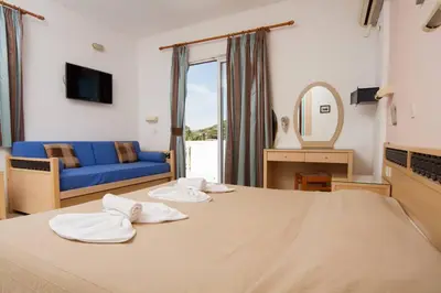 a bedroom with a large bed with a blue couch at White Palace Studios in Faliraki