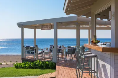 a restaurant on the beach with the ocean in the background at Rodos Palladium Leisure & Wellness in Faliraki