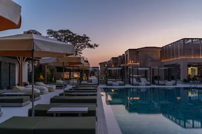 a hotel pool with lounge chairs and umbrellas at Eleonas Boutique Hotel & Spa - Adults Only in Ialyssos