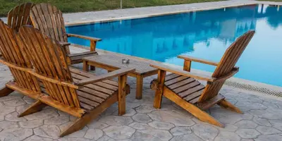 two wooden chairs and a table next to a swimming pool at Posidonia Luxury Villas Kolympia in Kolimbia