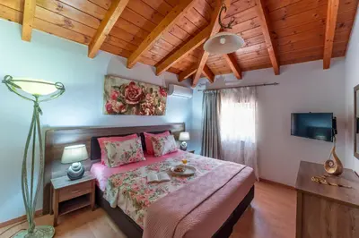 a bedroom with a bed with pink sheets and a television at Posidonia Luxury Villas Kolympia in Kolimbia