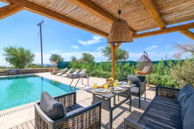 a patio with a table and chairs next to a swimming pool at Villa Elios Residence in Asklipiḯon