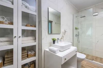 a white bathroom with a sink and a shower at Villa Elios Residence in Asklipiḯon