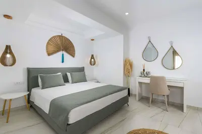a bedroom with a bed and a desk and mirror at Villa Elios Residence in Asklipiḯon