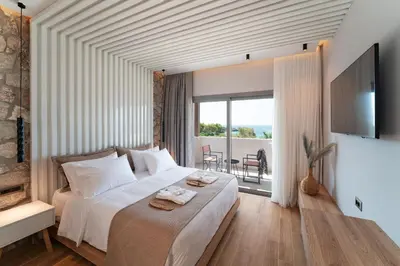 a bedroom with a large bed and a balcony at THERETRA PEFKI Seaside in Pefki Rhodes
