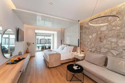 a bedroom with a bed and a stone wall at THERETRA PEFKI Seaside in Pefki Rhodes