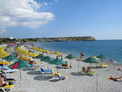 a beach with chairs and umbrellas and people on it at Renthub Villas at Kolympia in Kolimbia