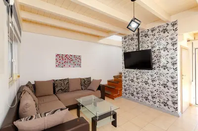 a living room with a couch and a tv on a wall at Renthub Villas at Kolympia in Kolimbia