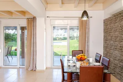 a dining room with a table and chairs and a window at Renthub Villas at Kolympia in Kolimbia