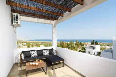 a balcony with a couch and a table at Villa Petalouda by Villa Plus in Kalathos