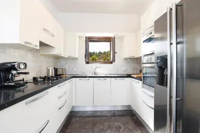 a white kitchen with white cabinets and a window at Villa Petalouda by Villa Plus in Kalathos