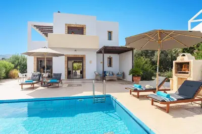 a villa with a swimming pool in front of a house at Villa Petalouda by Villa Plus in Kalathos