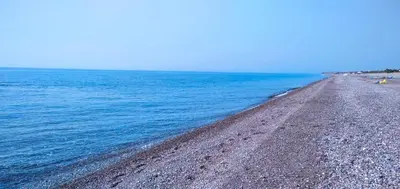 a beach with blue water and a rocky shore at Beachfront Studio Socrates in Gennadi