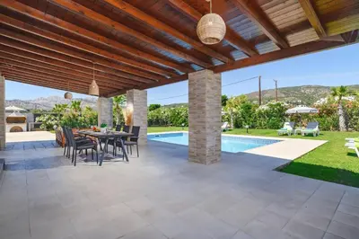 a patio with a table and chairs and a pool at Villa Kalathos by Villa Plus in Kalathos