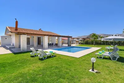 a backyard with a pool and chairs and a house at Villa Kalathos by Villa Plus in Kalathos