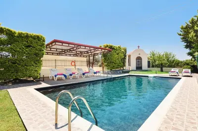 a swimming pool with chairs and a house at Villa Harmony Rhodes by Villa Plus in Koskinou