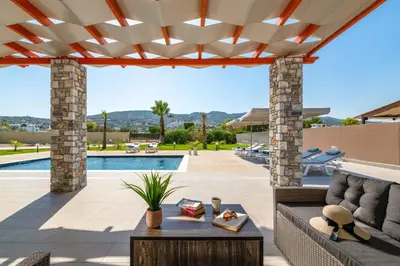 a patio with a couch and a table and a pool at Villa Elite Kalathos by Villa Plus in Kalathos