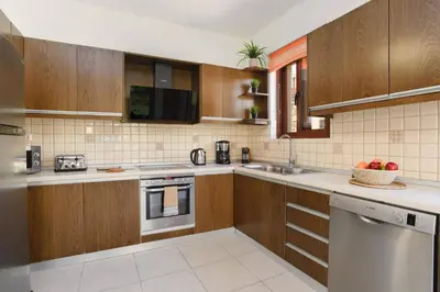 a kitchen with wooden cabinets and a sink and a dishwasher at Villa St Nicholas by Villa Plus in Pefki Rhodes