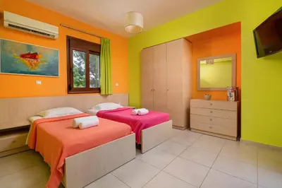 two beds in a room with orange and green at Villa St Nicholas by Villa Plus in Pefki Rhodes