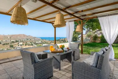 a patio with a table and chairs and a view of the ocean at Villa St Nicholas by Villa Plus in Pefki Rhodes