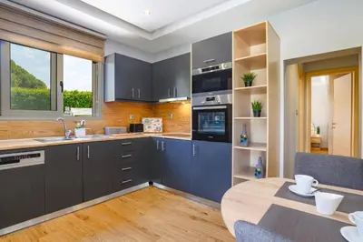a kitchen with gray cabinets and a wooden table at Villa Costa by Villa Plus in Ialyssos