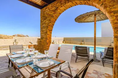 a patio with a table and chairs and a pool at Villa Kiotari by Villa Plus in Kiotari