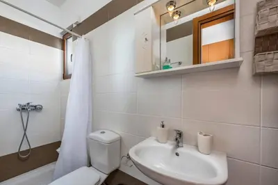 a bathroom with a sink and a toilet and a mirror at Villa Kiotari by Villa Plus in Kiotari