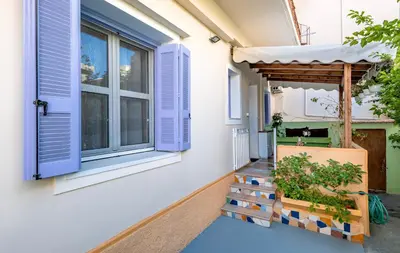 a house with blue shutters and a porch at Eddy's Apartment in Rhodes Town