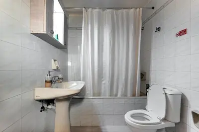 a white bathroom with a toilet and a sink at Eddy's Apartment in Rhodes Town