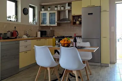 a kitchen with white chairs and a table with fruit on it at Piazza Masari in Haraki