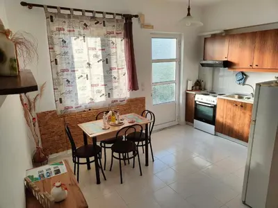 a kitchen with a table and chairs and a refrigerator at Hibiscus Green Apartments in Afantou
