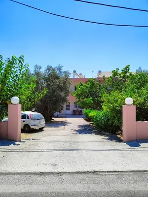 a car parked in front of a pink building at Hibiscus Green Apartments in Afantou