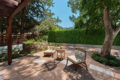 a patio with two chairs and a table and a tree at Dionysos Hotel in Ixia